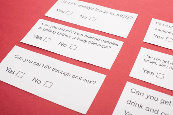 Cartes papier avec questionnaire VIH sur fond rouge — Photo de stock