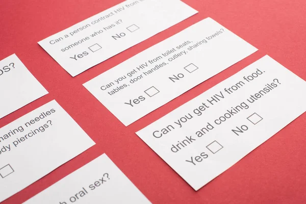 Cartes papier avec questionnaire VIH sur fond rouge — Photo de stock