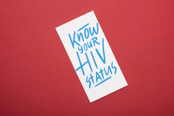 Vista superior do cartão com saber o seu status de HIV lettering no fundo vermelho — Fotografia de Stock