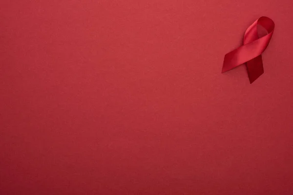 Top view of red awareness aids ribbon on red background — Stock Photo