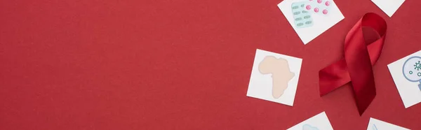 Vista superior de las tarjetas de papel y cinta roja de las ayudas de la conciencia sobre fondo rojo, tiro panorámico - foto de stock