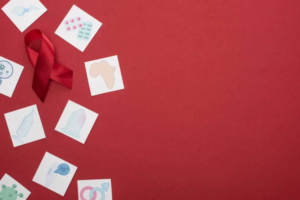 Vista superior de la cinta roja de las ayudas de la conciencia y de las tarjetas de papel sobre fondo rojo - foto de stock