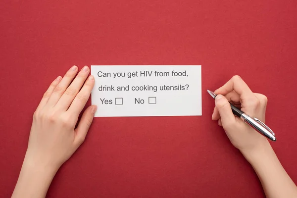 Vista recortada de la mujer que responde al cuestionario sobre el VIH sobre fondo rojo - foto de stock