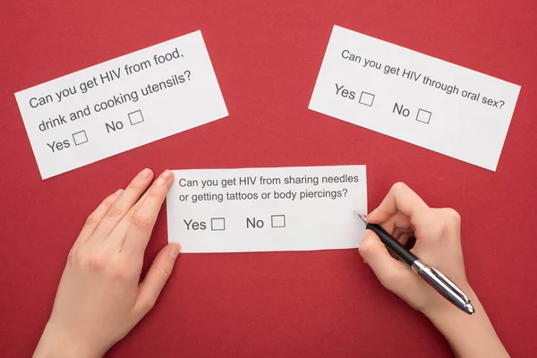 Обрезанный взгляд женщины, отвечающей на анкету по ВИЧ на красном фоне — стоковое фото
