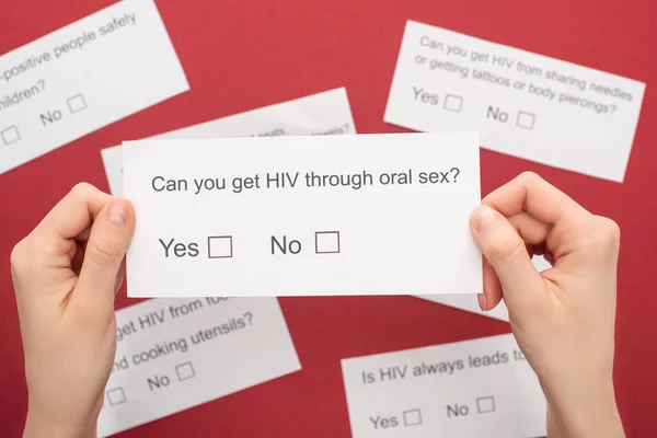 Vista parcial de la mujer que sostiene el cuestionario sobre el VIH sobre fondo rojo — Stock Photo