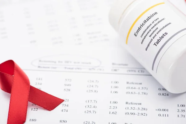 Nahaufnahme der Rückgabe für HIV-Testergebnisformular mit Stift, Awareness Ribbon und Behälter mit Emtricitabin-Tabletten — Stockfoto