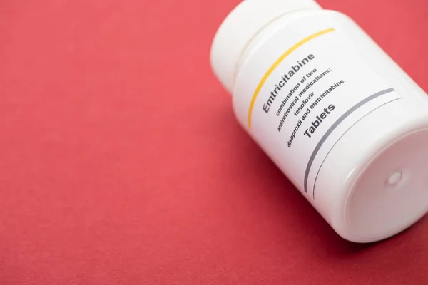 Behälter mit Emtricitabin-Tabletten auf rotem Hintergrund — Stockfoto