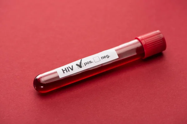 Prueba positiva de la muestra de sangre de hiv sobre fondo rojo - foto de stock