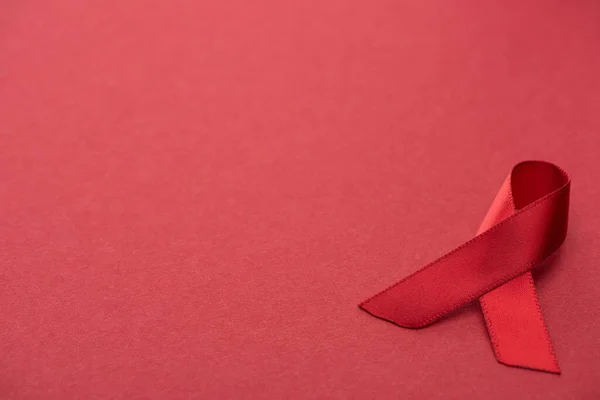 Red awareness aids ribbon on red background — Stock Photo