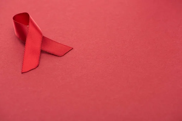 Consciência vermelha ajuda fita no fundo vermelho — Fotografia de Stock