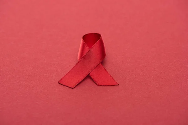 Red awareness aids ribbon on red background — Stock Photo