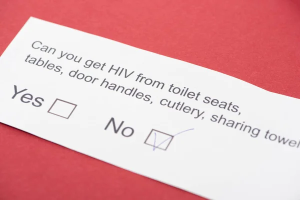 Tarjeta de papel con cuestionario sobre VIH sobre fondo rojo - foto de stock