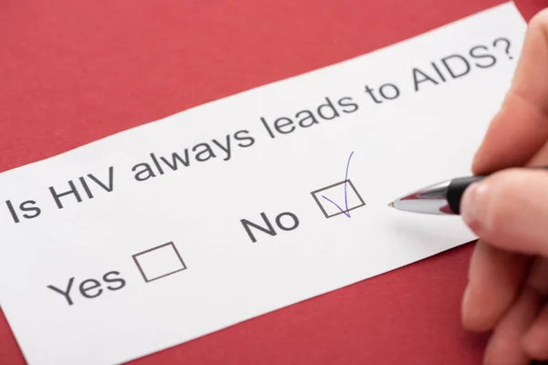 Cropped view of person answering HIV questionnaire on red background — Stock Photo