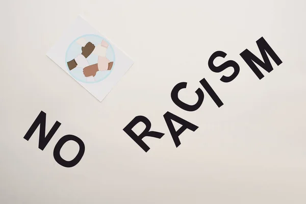 Top view of black no racism lettering and picture with multiethnic hands on white background — Stock Photo