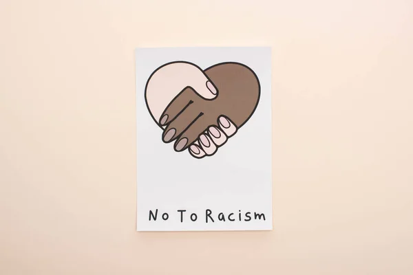Vue du dessus de l'image avec poignée de main multiethnique et non au lettrage raciste sur fond beige — Photo de stock