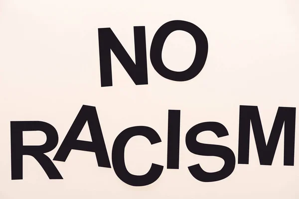 Top view of black no racism lettering isolated on beige — Stock Photo