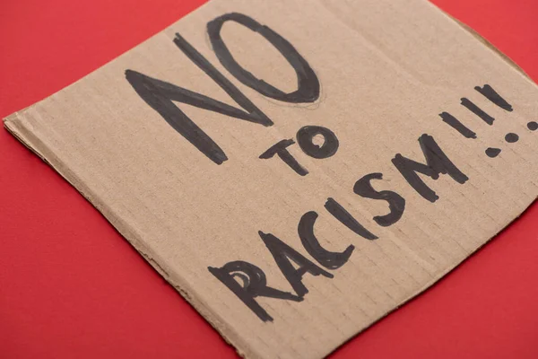 Cartello di cartone con dire no al razzismo lettering su sfondo rosso — Foto stock