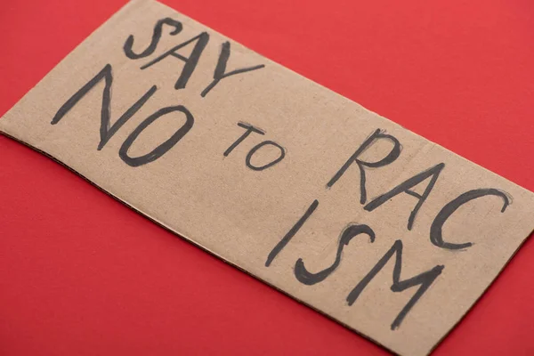 Carton placard with say no to racism lettering on red background — Stock Photo