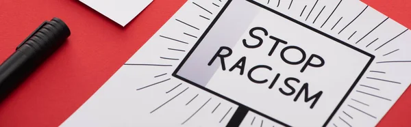 Черный маркер и картинка с нарисованной рукой и остановить расизм плакат на красном фоне, панорамный снимок — стоковое фото