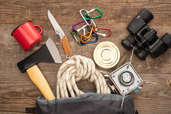 Blick von oben auf Wanderausrüstung im Rucksack auf Holzfläche — Stockfoto