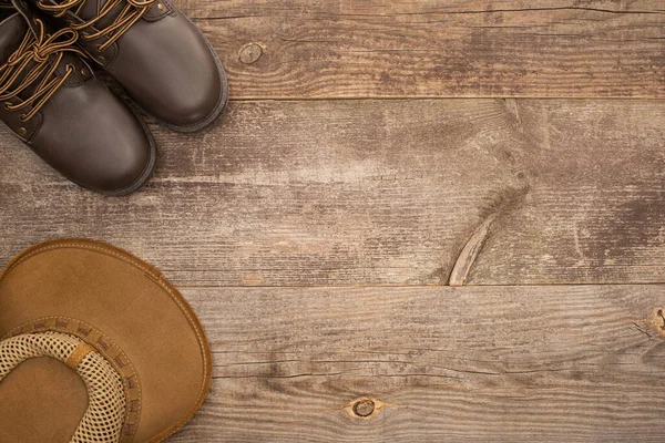 Vista dall'alto di stivali marroni e cappello su superficie di legno — Foto stock