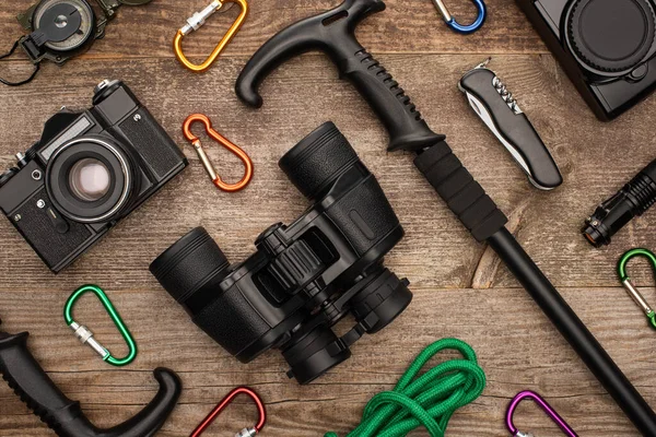Flat lay with hiking equipment binoculars and photo cameras on wooden table — Stock Photo