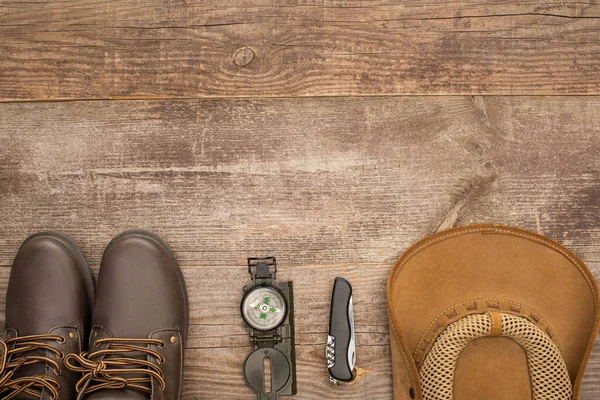 Vue de dessus des bottes, boussole, couteau et chapeau sur la table en bois — Photo de stock