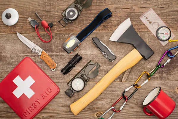 Top view of first aid kit and hiking equipment on wooden surface — Stock Photo