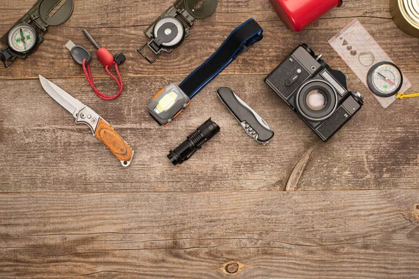 Vista superior de la cámara fotográfica y equipo de senderismo en mesa de madera - foto de stock