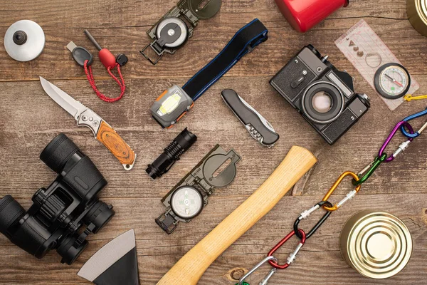 Vista superior de la cámara fotográfica, latas de lata y equipo de senderismo en la superficie de madera - foto de stock