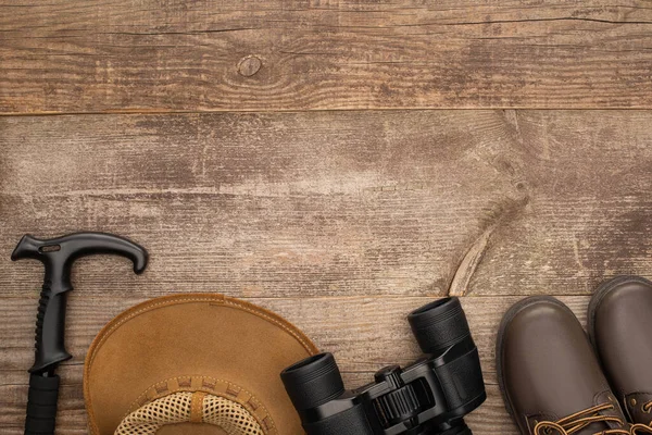 Blick von oben auf Wanderstock, Hut, Stiefel und Fernglas auf Holztisch — Stockfoto