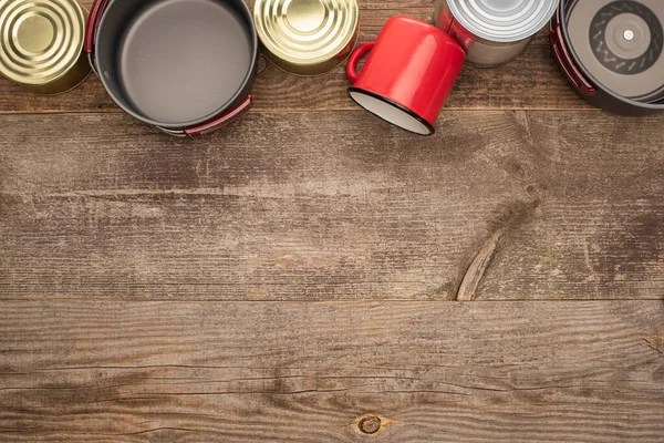 Vue de dessus des boîtes de conserve, des plats en métal et de la tasse sur la table en bois — Photo de stock