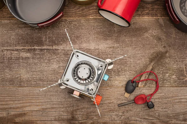 Vue de dessus du brûleur à gaz, briquet, vaisselle en métal et tasse sur table en bois — Photo de stock