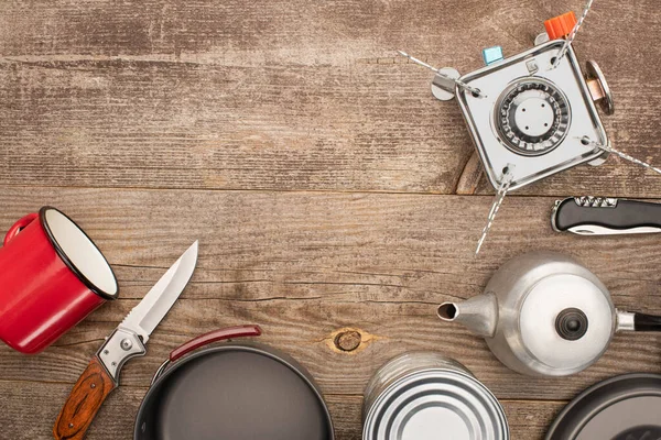 Draufsicht auf Teekanne, Gasbrenner, Metallbecher, Blechdose und Messer auf Holztisch — Stockfoto