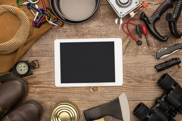 Draufsicht auf digitales Tablet mit schwarzem Bildschirm in der Nähe von Wanderausrüstung auf Holztisch — Stockfoto