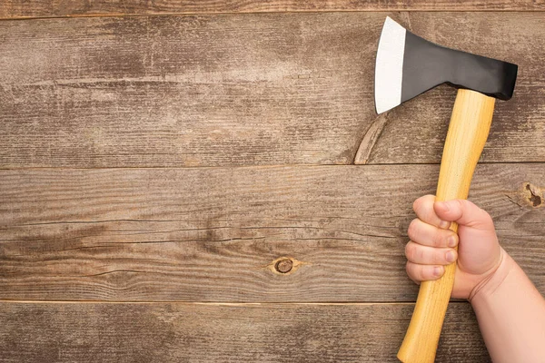 Partial view of man holding axe on wooden table — Stock Photo
