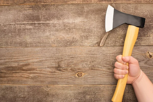 Vista parcial del hombre sosteniendo hacha en la mesa de madera - foto de stock