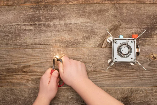 Partial view of man lighting spark near gas burner on wooden table — Stock Photo