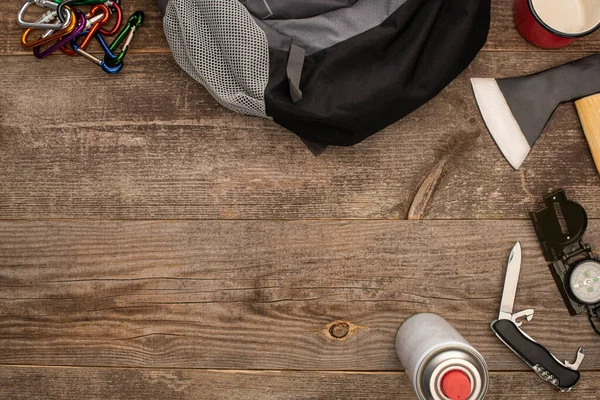 Blick von oben auf Rucksack in der Nähe von Wanderausrüstung auf Holzuntergrund — Stockfoto