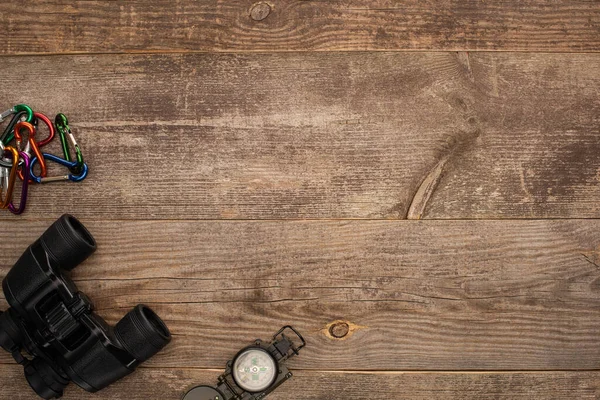 Вид сверху на карабины, бинокль и компас на деревянный стол — стоковое фото