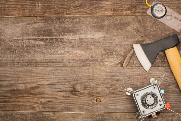 Top view of gas burner, axe and compass on wooden surface — Stock Photo