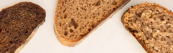 Top view of fresh brown bread slices on white background, panoramic shot — Stock Photo