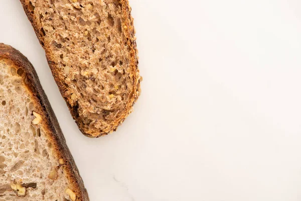 Вид зверху зі свіжих шматочків коричневого хліба на білому фоні — стокове фото