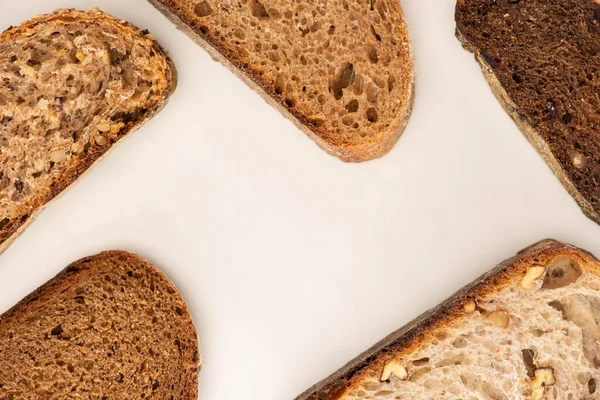 Vista dall'alto di fette di pane fresco marrone su sfondo bianco — Foto stock