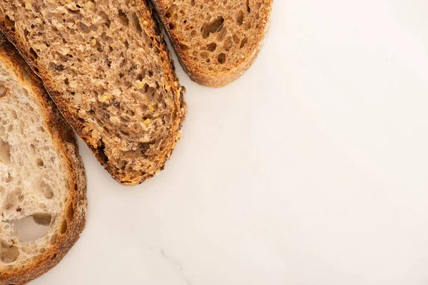 Vista dall'alto di fette di pane fresco marrone su sfondo bianco — Foto stock