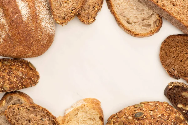 Draufsicht auf frische braune Brotscheiben und Laibe auf weißem Hintergrund — Stockfoto