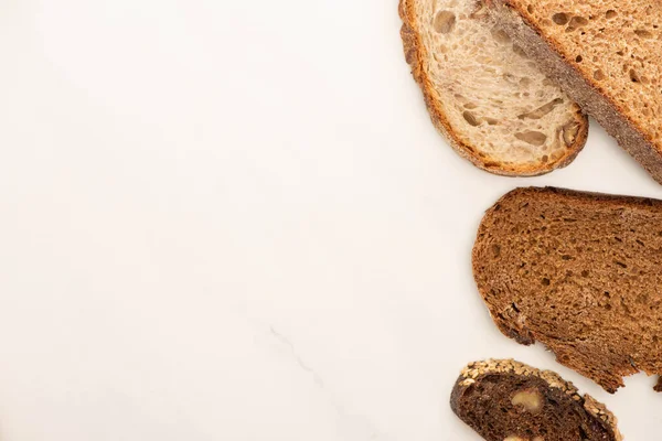 Вид зверху на свіжі шматочки цільного зерна хліба на білому тлі — стокове фото