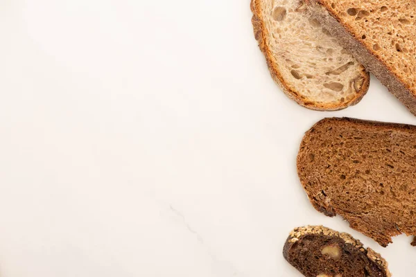 Vue de dessus des tranches de pain de grains entiers frais sur fond blanc — Photo de stock