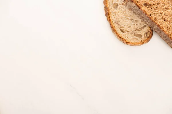 Vista superior de rebanadas frescas de pan de grano entero sobre fondo blanco - foto de stock