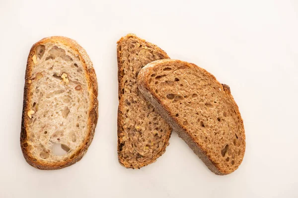 Vista superior de rebanadas frescas de pan de grano entero sobre fondo blanco - foto de stock